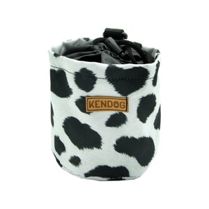 May include: A white and black cow print dog treat pouch with a brown leather patch that says "KENDOG".
