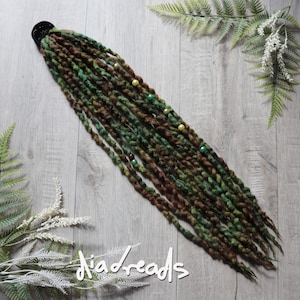 May include: A set of synthetic dreadlocks in shades of forest green and dark brown, attached to a black hair tie. The dreadlocks feature a twisted texture and are accented with small, round beads in yellow, green, and brown colors.
