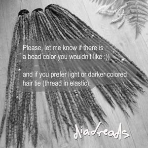 May include: Three sets of long, textured synthetic dreadlocks in varying shades of gray and brown, each secured with a black hair tie. The dreadlocks are adorned with small, round metallic beads and include text overlay regarding bead and hair tie preferences.