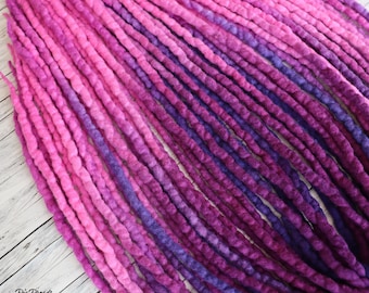May include: A set of pink and purple ombre wool dreadlocks. The dreadlocks are made of wool and are approximately 61 cm long.