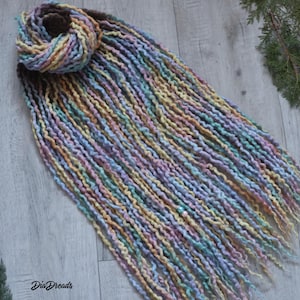 May include: A set of long, colorful wool dreadlocks with a light blue bead. The dreadlocks are a mix of pastel colors, including pink, yellow, blue, and green.