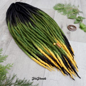 May include: Black, green and yellow ombre wool dreadlocks with a wooden bead accent.