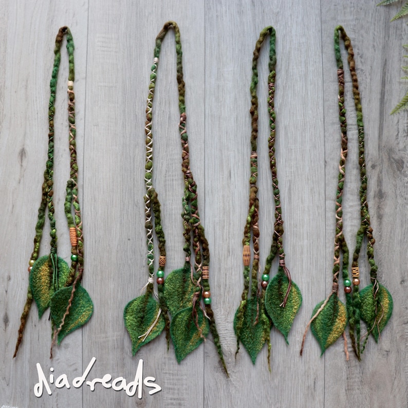 May include: Four sets of green and brown hair extensions featuring felted leaf accents, braided textures, and small wooden and metallic beads. The extensions are arranged vertically, and the text "diadreads" is visible in the bottom left corner.