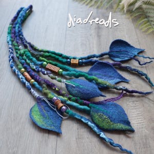 May include: A set of blue, green, and purple felted hair extensions featuring the text "diadreads" at the top. The strands are decorated with various beads and end in leaf-shaped felt accents in shades of blue and green.