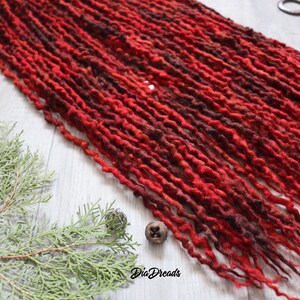 May include: A close-up of a bundle of red and brown wool dreadlocks. The dreadlocks are arranged in rows and have a wavy texture.