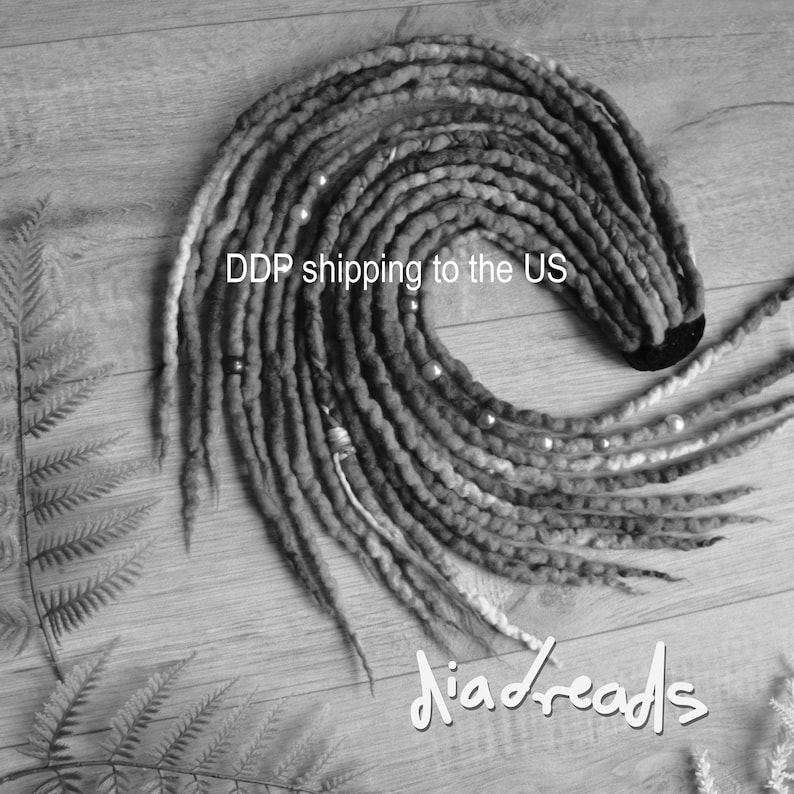 May include: A set of black and grey synthetic dreadlocks arranged in a circular spiral pattern. The dreadlocks feature various beads and decorative wraps along their length. The text DDP shipping to the US and diadreads is visible.