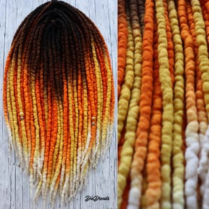 May include: A set of handmade dreadlocks in a gradient of colors, transitioning from dark brown to orange, yellow, and white at the tips. The dreads are adorned with small, decorative beads. The text "Dia Dreads" is visible at the bottom.