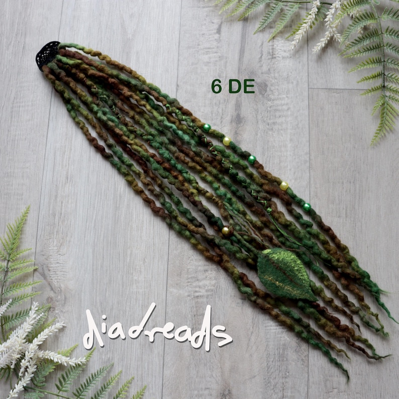 May include: A set of six double-ended synthetic dreadlocks in shades of forest green, olive, and dark brown. The dreads feature small green, yellow, and white beads, along with a single textured green leaf-shaped charm attached to one strand.
