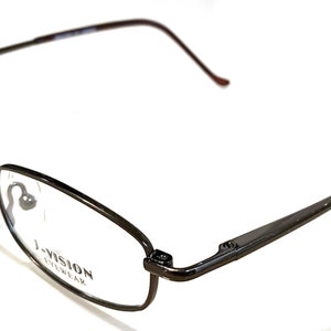 May include: A pair of black metal eyeglasses with a rectangular frame and clear lenses. The arms of the glasses are made of a thin metal and have a spring hinge. The glasses have the text "I-VISION EYEWEAR" printed on the right lens.