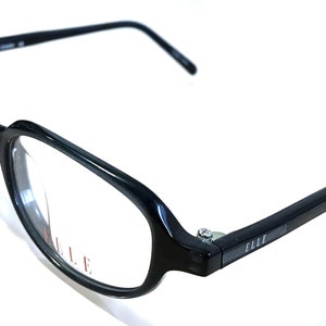 Pode incluir: Óculos de armação de plástico preto com lentes transparentes. O nome da marca "ELLE" está impresso nas hastes dos óculos.