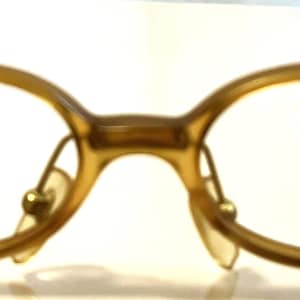 Könnte beinhalten: Eine goldfarbene Brille mit ovalen Gläsern und klaren Gläsern.