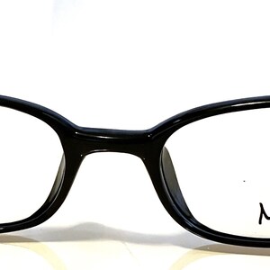 K&ouml;nnte beinhalten: Schwarze, ovale Brille mit dem Wort "Max" auf dem rechten Glas. Die Fassungen sind gl&auml;nzend und die B&uuml;gel sind d&uuml;nn. Die Brille ist vor einem wei&szlig;en Hintergrund platziert.