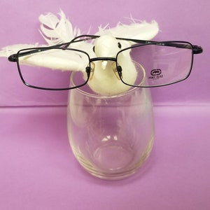 Puede incluir: Gafas rectangulares negras con un pájaro blanco posado en el puente de las monturas. Las gafas tienen el texto "marc ecko" impreso en la lente derecha.