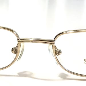 Könnte beinhalten: Goldfarbene Metallbrille mit rechteckigem Gestell und klaren Gläsern. Der Markenname "SORMANI ITALY" ist auf dem rechten Glas aufgedruckt.