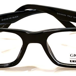 May include: Black rectangular eyeglasses with a GIOVANNI Italy EYEWEAR logo on the right lens. The frame is made of plastic and has a classic design.