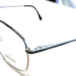 May include: Silver-toned rectangular eyeglasses with a black accent on the arms. The glasses have a clear lens and the brand name "Lightfinders" is printed on the right lens.