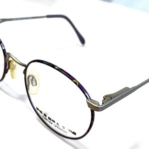 Może przedstawiać: Okulary okrągłe w kolorze srebrnym i fioletowym z napisem "MIRION NEW YORK" na oprawce.