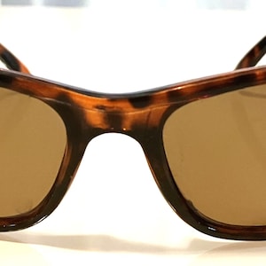 Könnte beinhalten: Schildkröten-Sonnenbrille mit braunen Gläsern. Die Sonnenbrille hat eine klassische, leicht geschwungene Form.