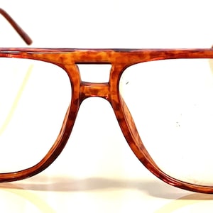 May include: Tortoise shell aviator style eyeglasses with gold metal arms.