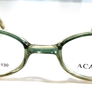 Könnte beinhalten: Grüne ovale Kunststoffbrille mit dem Text "ACADEMIC" auf der rechten Linse und "P2001 37□18-130" auf der linken Linse.