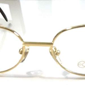 May include: Gold-tone metal eyeglasses with oval-shaped lenses and a Focuss logo on the right lens.