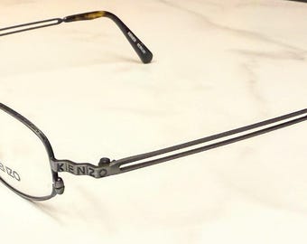 Occhiali da vista Kenzo KE8630, nuovi, mai indossati, in pelle nera opaca/grigio canna di fucile con montatura decorata e dettagli KENZO. Montatura con aste aperte, fuori produzione.