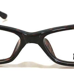 Könnte beinhalten: Schildpatt-Brille mit klaren Gläsern und dem Wort "Max" auf dem rechten Glas.