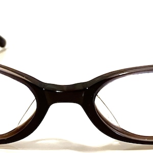 Puede incluir: Un par de gafas ovaladas de color marrón con un marco marrón oscuro.