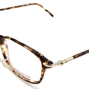 Könnte beinhalten: Schildpatt-Brille mit goldenen Akzenten und dem Wort "ORDACHE" auf dem Rahmen.