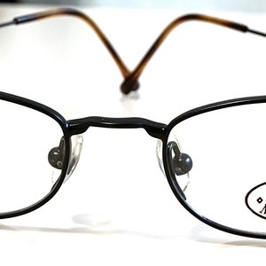 Könnte beinhalten: Schwarze Metallgestellbrille mit einem Steve Madden Logo auf der rechten Linse.