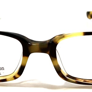 May include: Tortoise shell eyeglasses with a clear lens and the text "Calliope Collection Star Bright Optical" on the frame.