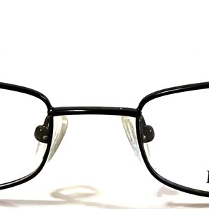 May include: Black rectangular eyeglasses with a thin metal frame. The brand name "ROSSINI" is printed on the right lens in red and black.