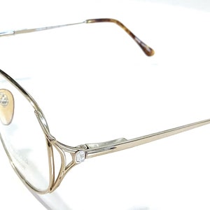 May include: Gold-tone metal eyeglasses with clear lenses and tortoiseshell temple tips.