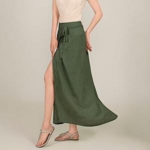 May include: A green wrap skirt with a side slit and a tie at the waist. The skirt is made of a lightweight fabric and is perfect for warm weather.