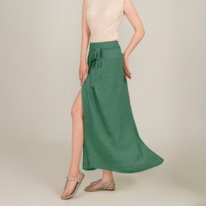 Può includere: Una gonna verde avvolgente con uno spacco laterale e un nodo in vita. La gonna è realizzata in un tessuto leggero e ha una silhouette fluida.