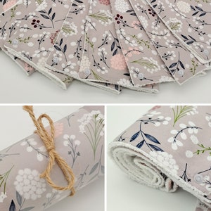 May include: A set of 10 gray fabric burp cloths with a white floral pattern and a white border. The cloths are soft and absorbent, making them ideal for wiping up spills and drool.
