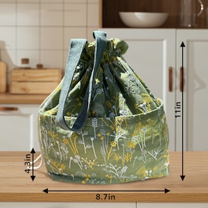 May include: Green drawstring bag with a floral pattern and two handles. The bag measures 8.7 inches wide and 11 inches tall.