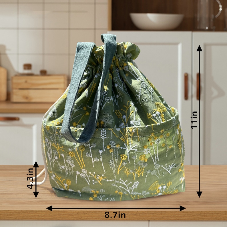 May include: Green drawstring bag with a floral pattern and two handles. The bag measures 8.7 inches wide and 11 inches tall.