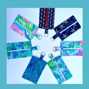 May include: Seven zippered pouches with various nautical themed prints. The pouches are arranged in a circle with the zippers facing outwards. The prints include anchors, seahorses, starfish, and a floral pattern.