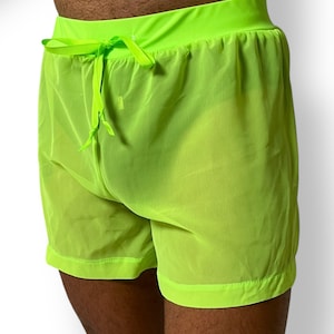 May include: Neon green shorts with a drawstring waist. The shorts are made of a sheer, lightweight fabric. The waistband and hem are a solid neon green.