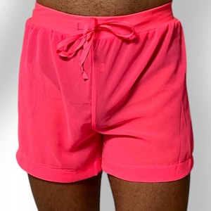 May include: Bright pink shorts with a drawstring waist. The shorts are made of a lightweight material and have a relaxed fit. The shorts are a vibrant neon color.