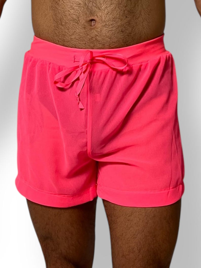 May include: Bright pink shorts with a drawstring waist. The shorts are made of a lightweight material and have a relaxed fit. The shorts are a vibrant neon color.