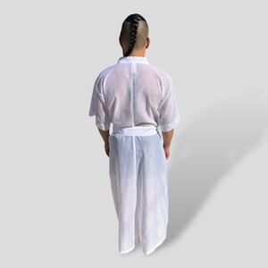Op de afbeelding: Een witte, doorschijnende badjas met een lang, vloeiend ontwerp. De badjas heeft een riem en een kraag.
