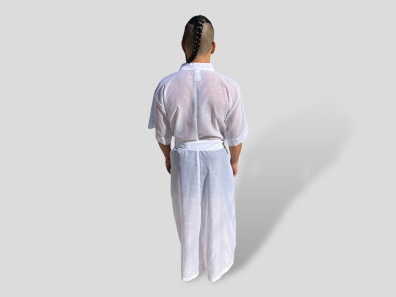Op de afbeelding: Een witte, doorschijnende badjas met een lang, vloeiend ontwerp. De badjas heeft een riem en een kraag.