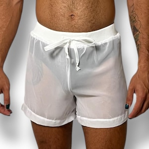 May include: White sheer shorts with a drawstring waist. The shorts have a white trim along the bottom hem and waistband. The fabric is lightweight and slightly transparent.