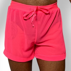 May include: Bright pink shorts with a drawstring waist. The shorts are made of a lightweight, possibly sheer fabric. The shorts have a relaxed fit and are suitable for casual wear or athletic activities.