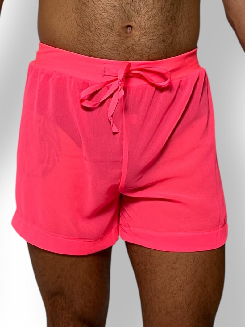 May include: Bright pink shorts with a drawstring waist. The shorts are made of a lightweight, possibly sheer fabric. The shorts have a relaxed fit and are suitable for casual wear or athletic activities.