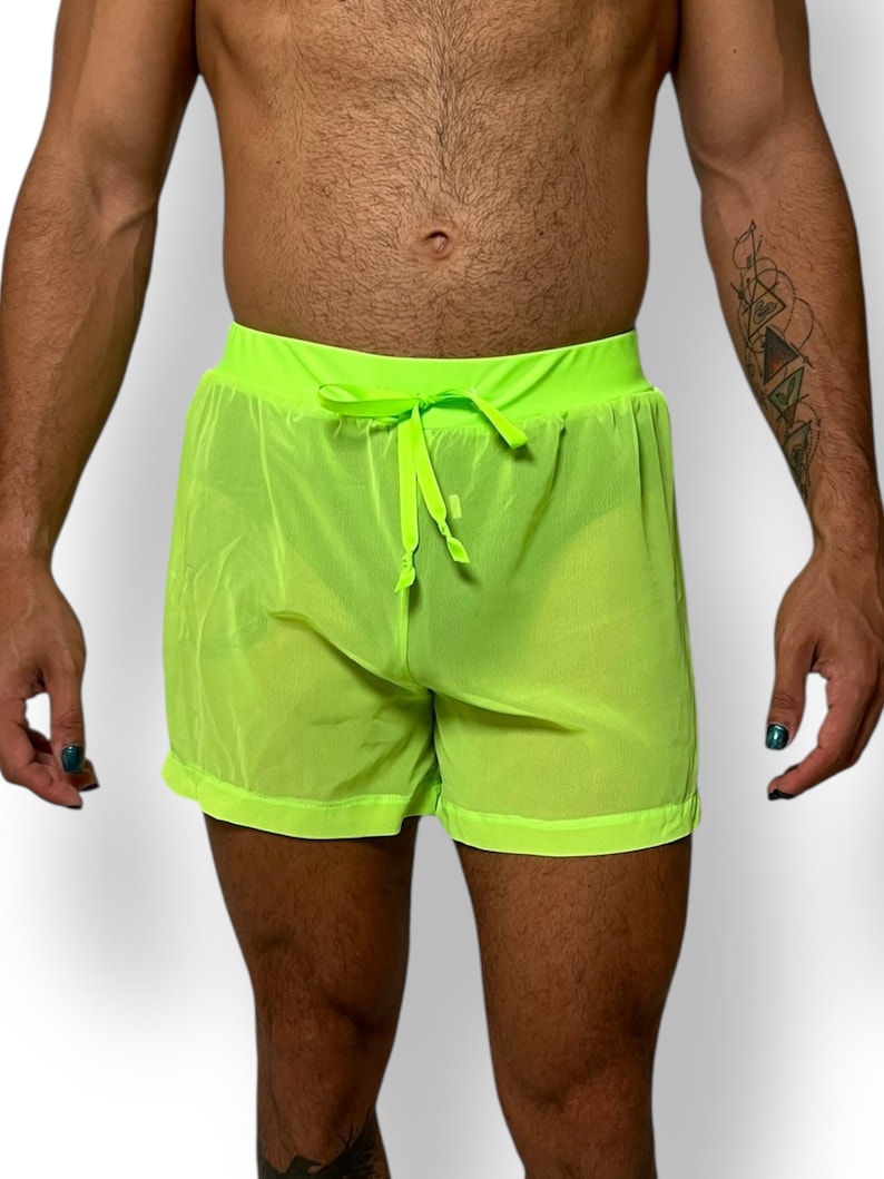 May include: Neon green mesh shorts with a drawstring waist. The shorts are made of a lightweight, sheer fabric. The shorts have a relaxed fit and are suitable for swimwear or casual wear.