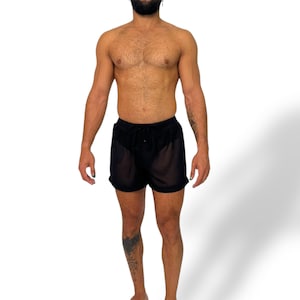 May include: Black sheer shorts with a drawstring waist. The shorts are made of a lightweight, see-through fabric. The model is standing in front of a white background.