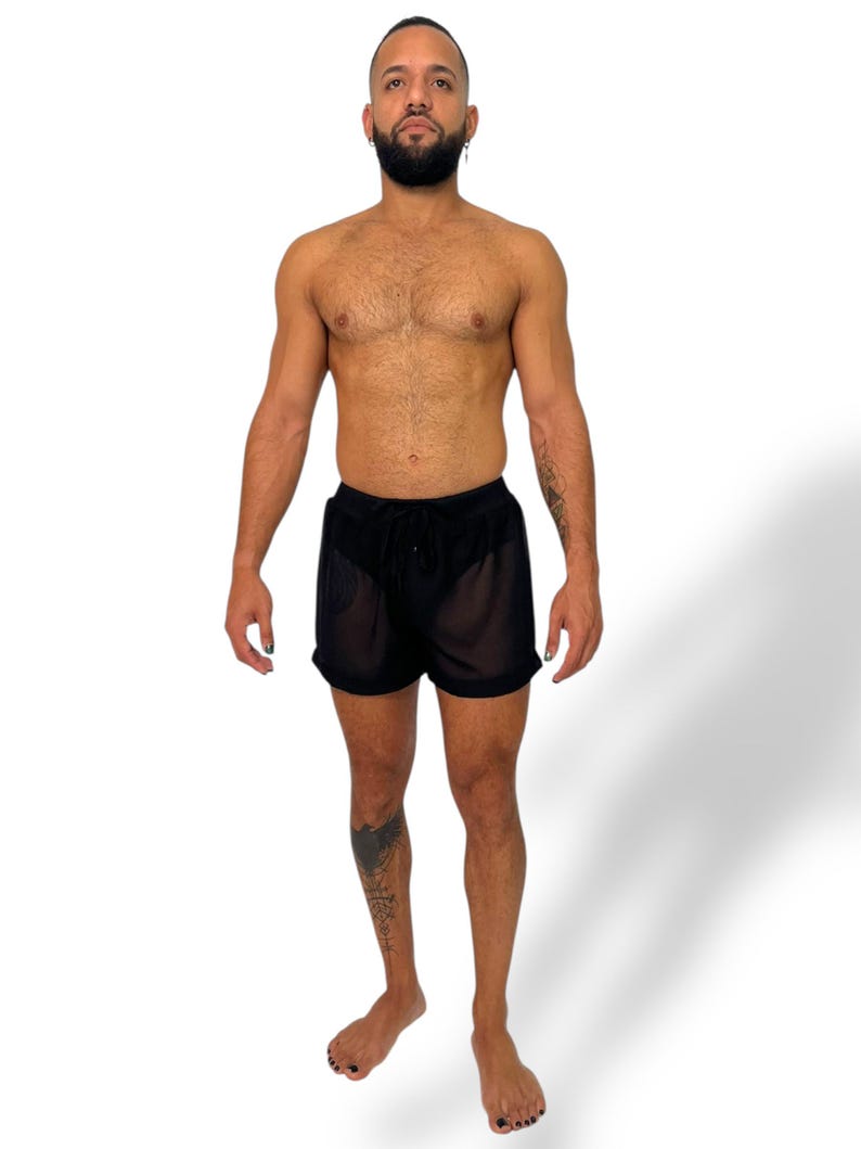 May include: Black sheer shorts with a drawstring waist. The shorts are made of a lightweight, see-through fabric. The model is standing in front of a white background.
